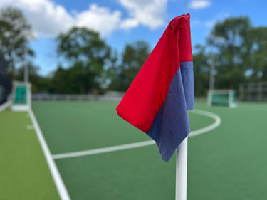 Cornervlag op hockeyveld in kleuren rood en blauw horizontaal gestreept